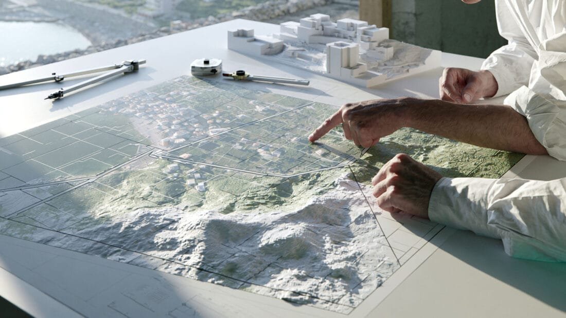 Vorsorgeplan Montenegro -Zwei Personen prüfen eine topografische Karte und Architekturmodelle für eine Standortplanung.